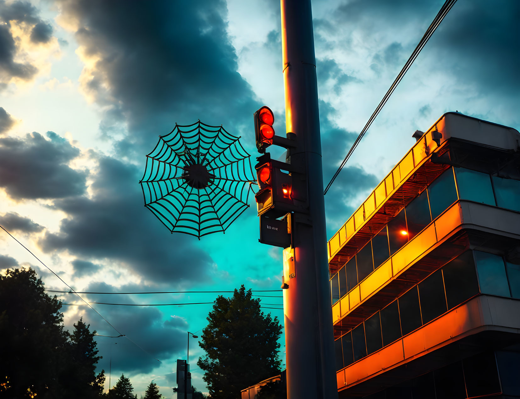 Spiderweb on Street Light Pole with Red Traffic Light and Evening Sky