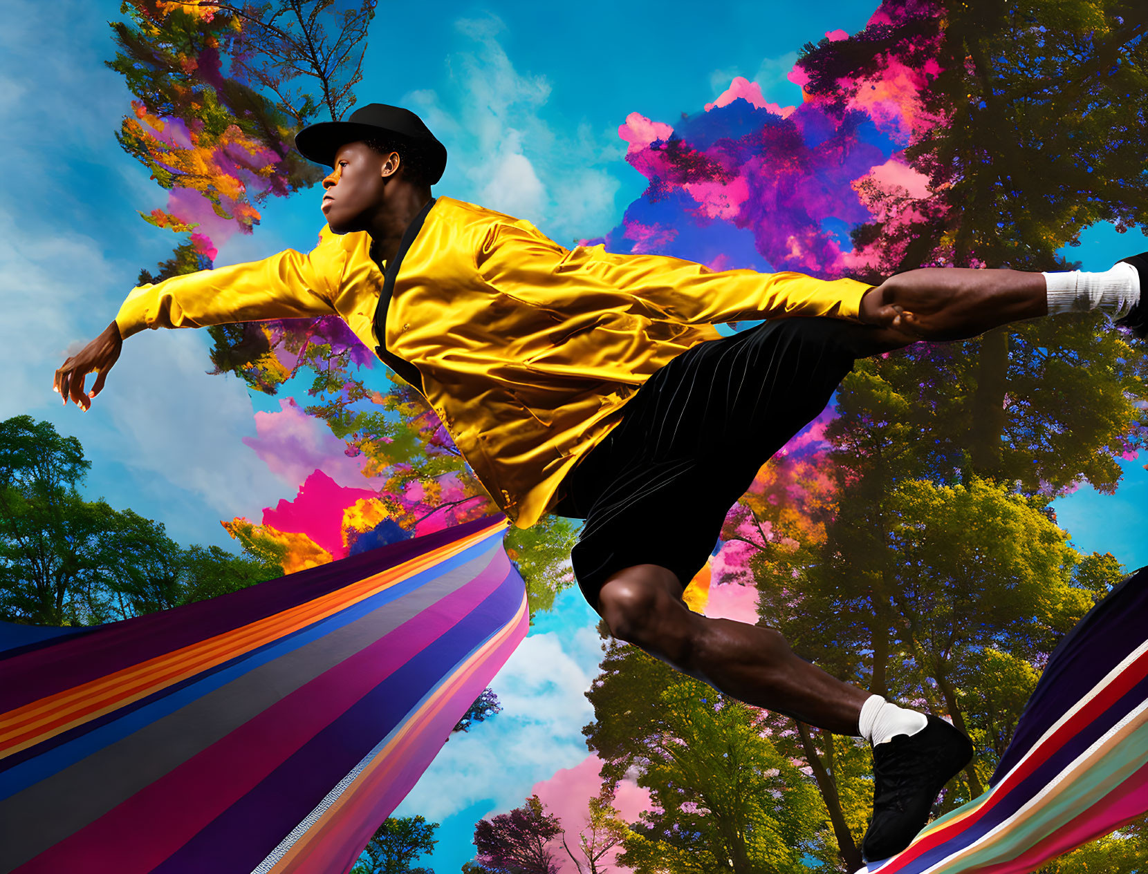 Man in yellow jacket jumps over colorful hammock against sky and foliage