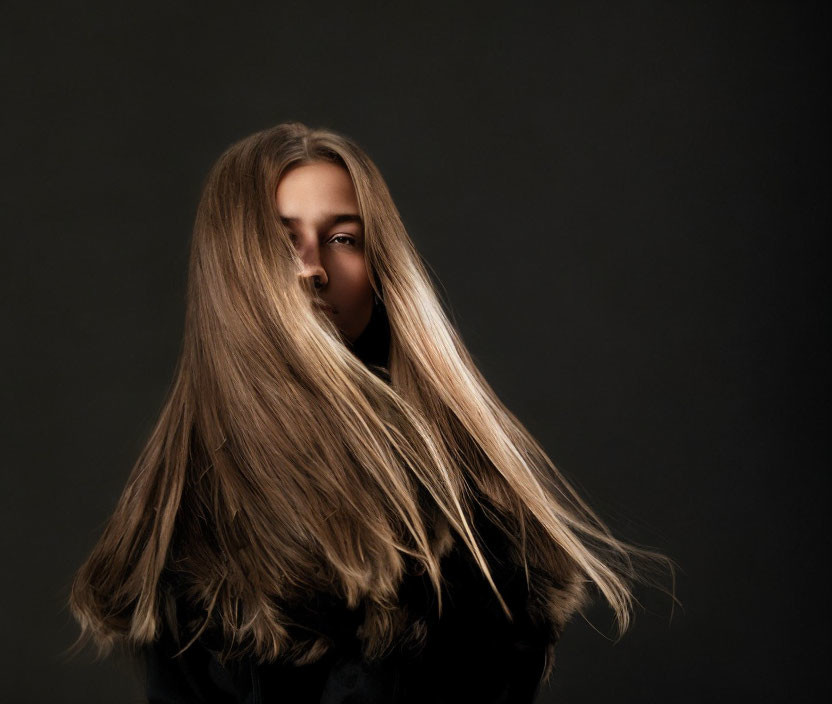 Portrait of a woman with long, flowing hair on dark background