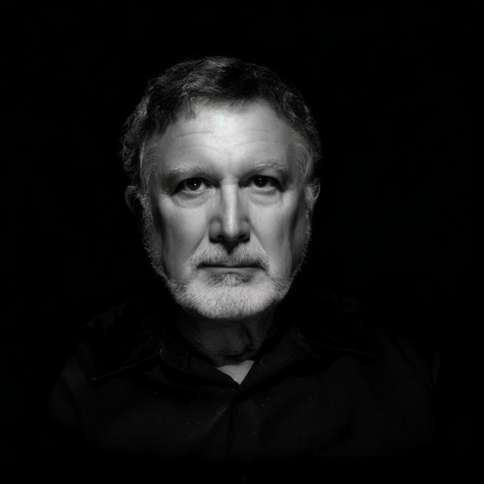 Monochromatic portrait of middle-aged man with beard on black background