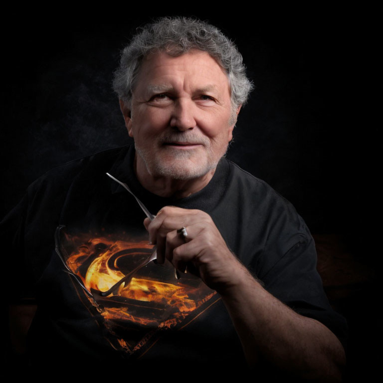 Grey-haired man in fiery graphic tee with smoking pipe