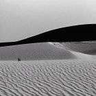 Desert landscape with sand dunes, futuristic building, and smoke plumes under dark sky