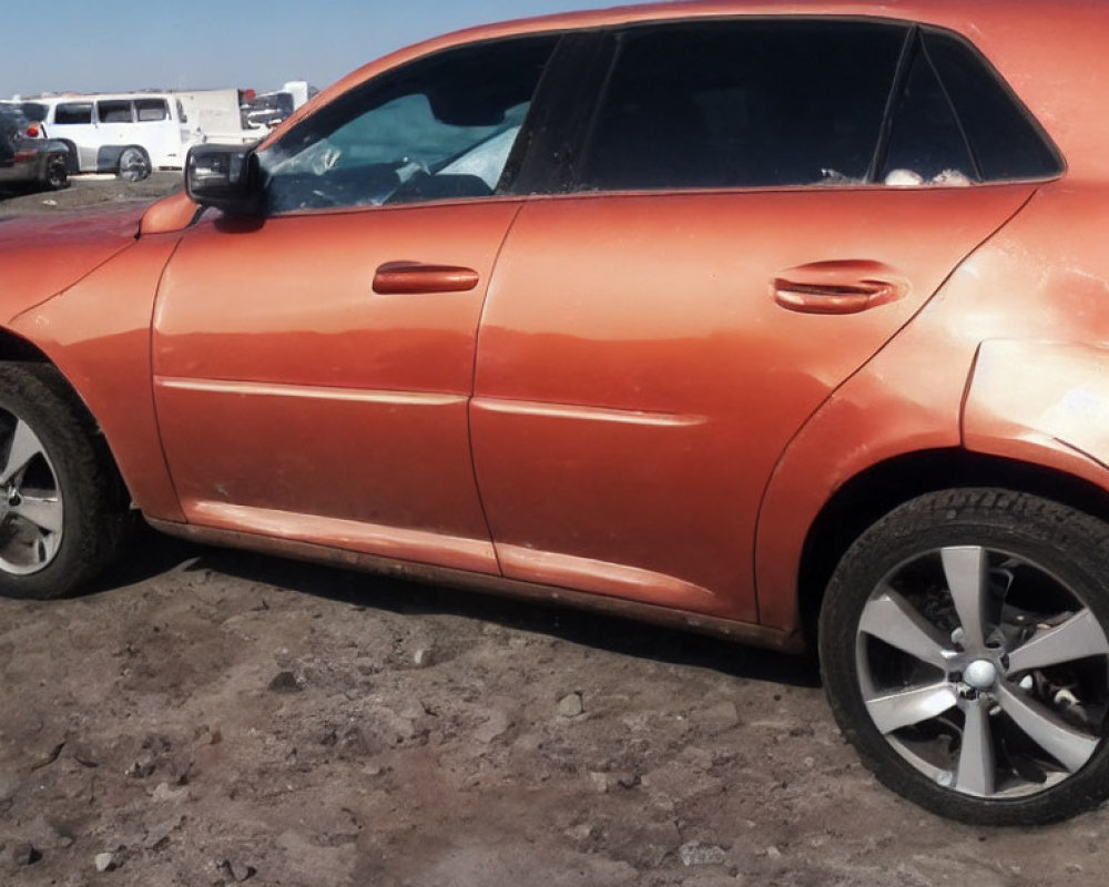 Orange glossy car parked on dusty ground under clear blue sky