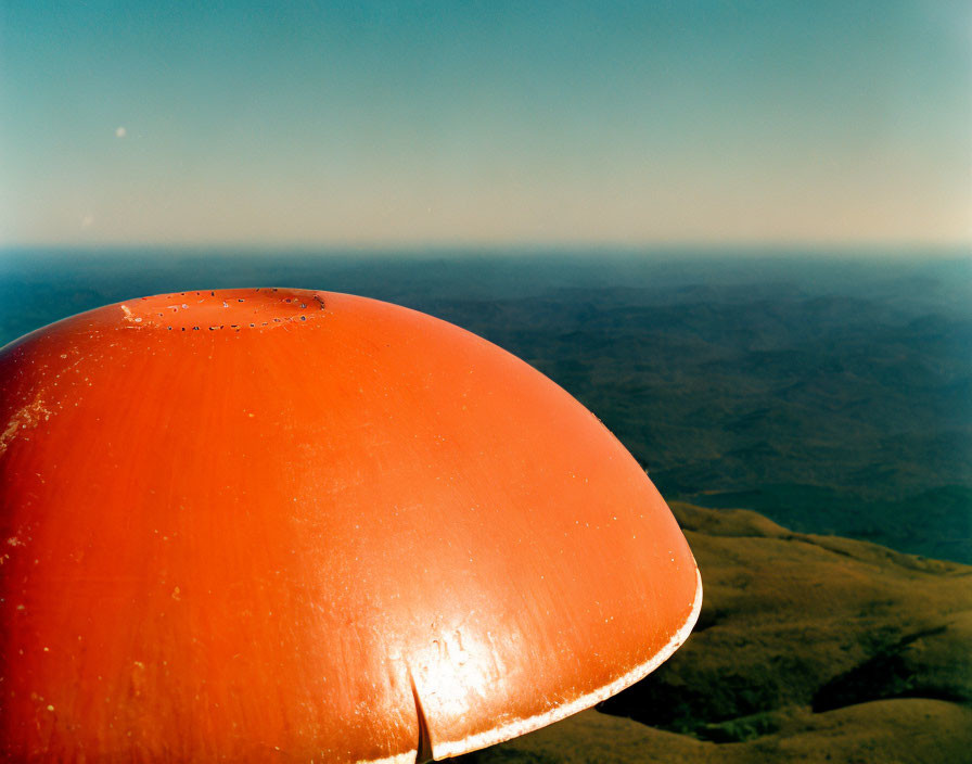 Dome-shaped object against rolling hills under clear blue sky