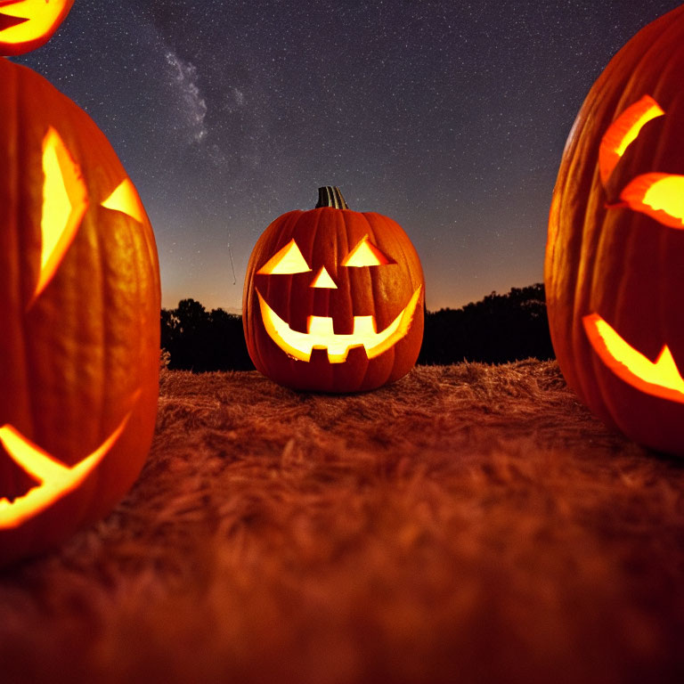 Glowing jack-o'-lanterns under starry night sky