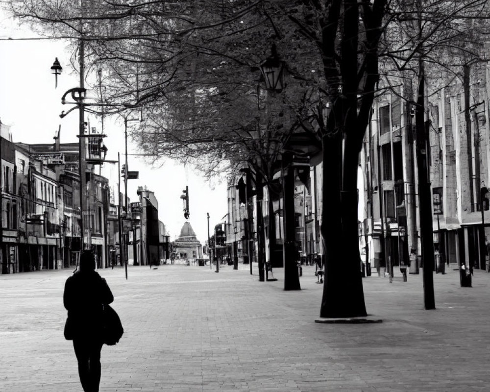 Urban street scene with lone person walking among buildings and trees