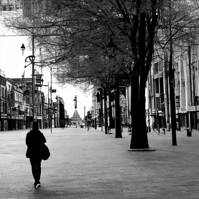 Urban street scene with lone person walking among buildings and trees