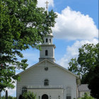 White church with steeple in misty forest with stream and ethereal light