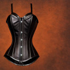 Black Corset with Front Clasps and Lace Trim on Orange Textured Background