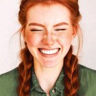 Portrait of young woman with red braided hair, freckles, green eyes, butterfly clips,