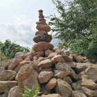 Tranquil landscape with balanced stones, vibrant trees, and clear blue sky