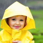 Smiling child in yellow hooded outfit against green backdrop