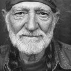 Monochrome portrait of a man with cap, beard, and smile