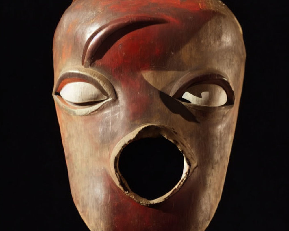 Carved wooden mask with serene expression on black background