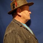 Man in Profile with Brown Hat and Coat on Blue Background