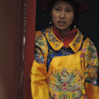 Portrait of Woman in Traditional Asian Attire with Yellow Robe, Red Headdress, and Blue Scar