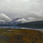 Serene landscape with misty mountains, tranquil lake, fields, and red-roofed houses