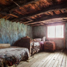 Unmade beds, worn furniture, wooden beams in rustic attic bedroom