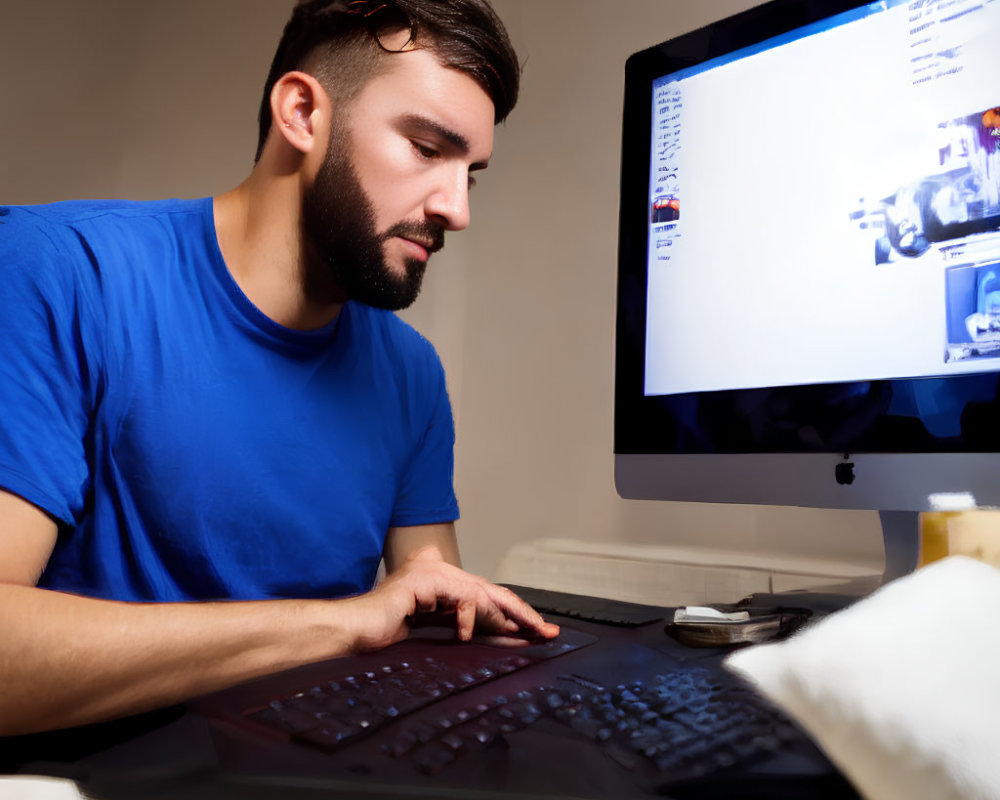 Bearded man using graphic tablet and computer in dimly lit room