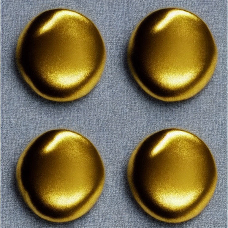 Four Gold Metallic Buttons on Textured Gray Fabric