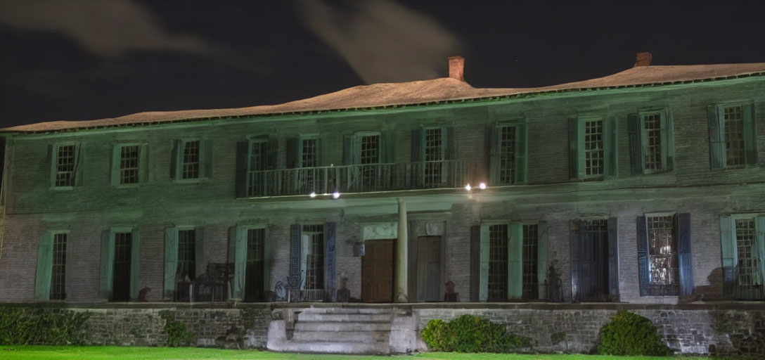 Two-story historic building at night with illuminated windows and grand staircase