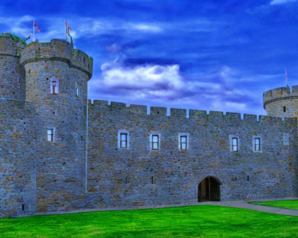 Stone medieval castle with twin towers in lush greenery under blue sky