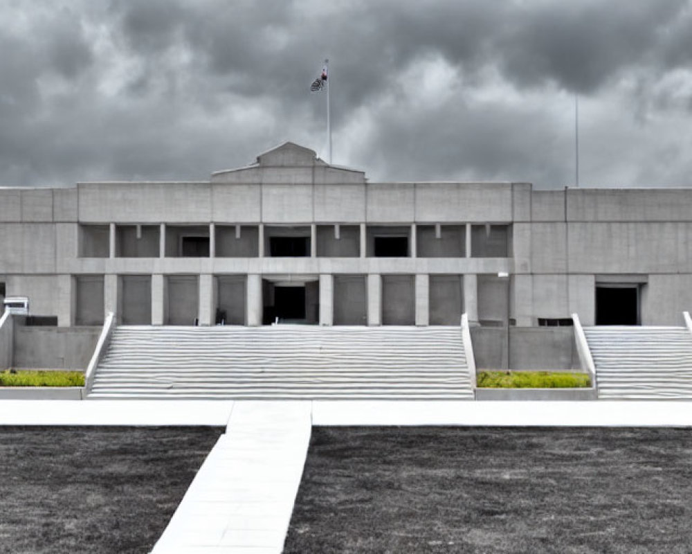 Symmetrical modern building with central entrance and flag under overcast sky