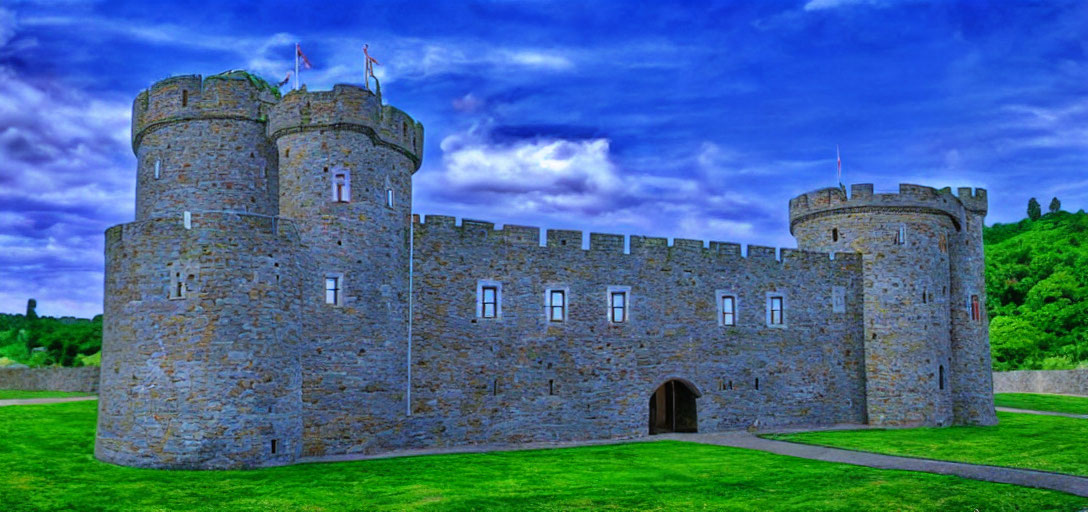 Stone medieval castle with twin towers in lush greenery under blue sky