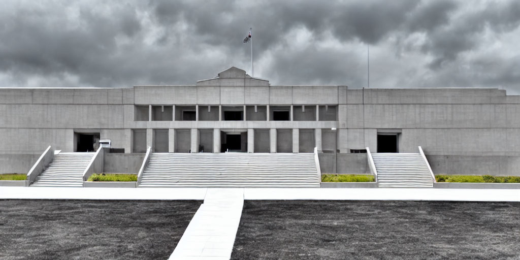 Symmetrical modern building with central entrance and flag under overcast sky