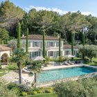 Spacious mansion with pool and lush gardens under blue sky