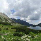 Scenic landscape with church spire, sheep, trees, waterfall, and cloudy sky