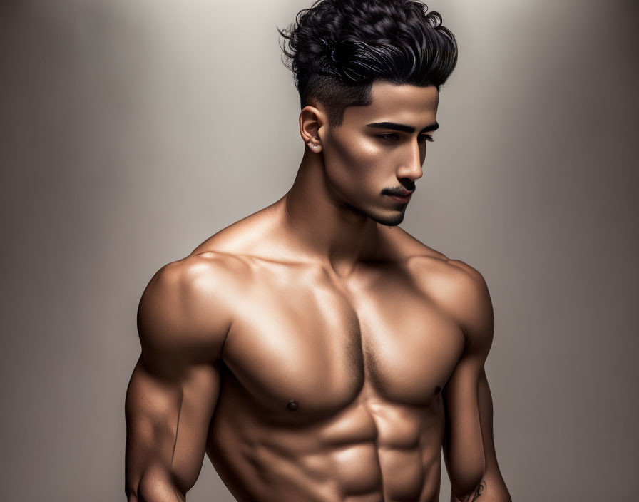 Muscular shirtless man posing with styled hair on neutral background