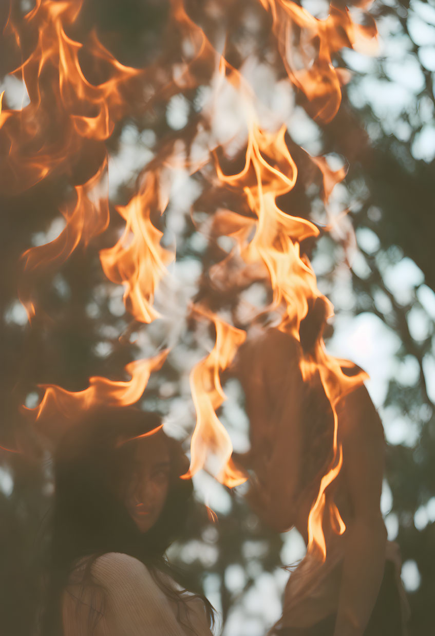 Silhouette of a person amidst dancing flames and tree branches