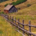 Rustic cabin in vibrant meadow with wildflowers & old wooden fence