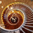 Luxurious room with elegant spiral staircase, stone walls, ornate railings, small library, and