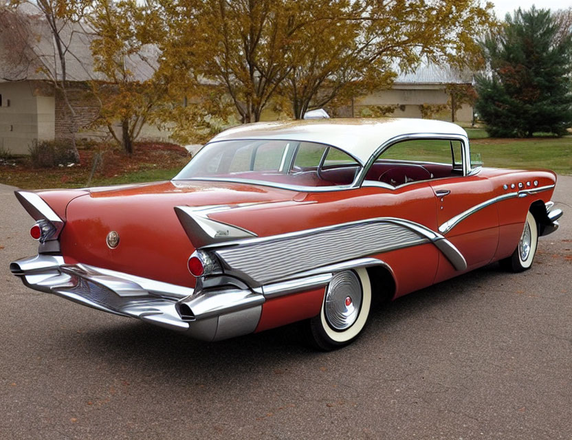 Vintage red and white car with tail fins and chrome details on asphalt road