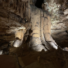 Majestic subterranean cave with stalactites, waterfalls, and serene pool