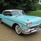 Classic Turquoise Car with Tailfins and White Sidewall Tires in Desert Setting