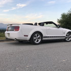 Convertible sports car parked with mountains in background.