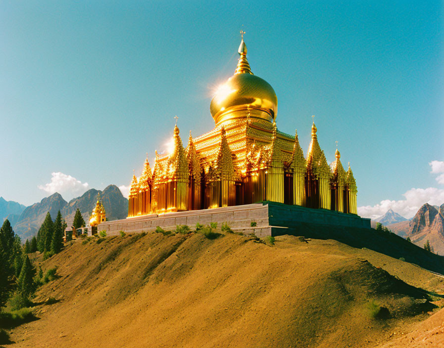 Golden-domed temple with ornate spires in mountainous landscape