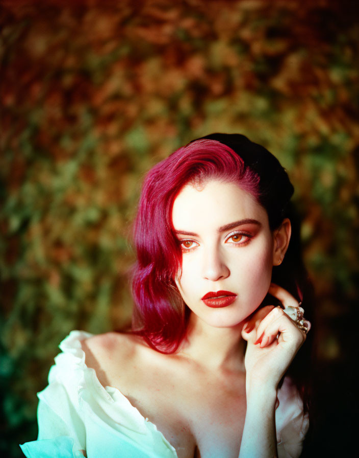 Vibrant red-haired woman in white blouse against leafy background