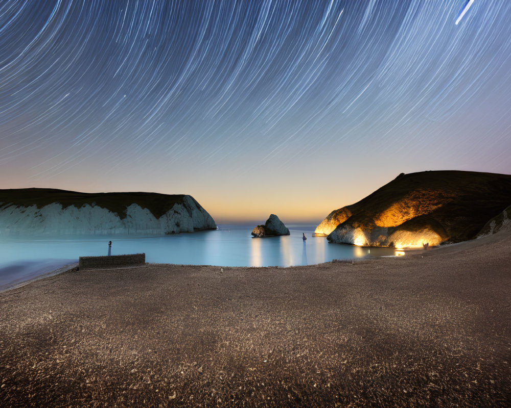 Nighttime Coastal Scene: Star Trails, White Cliffs, Lit Beachfront