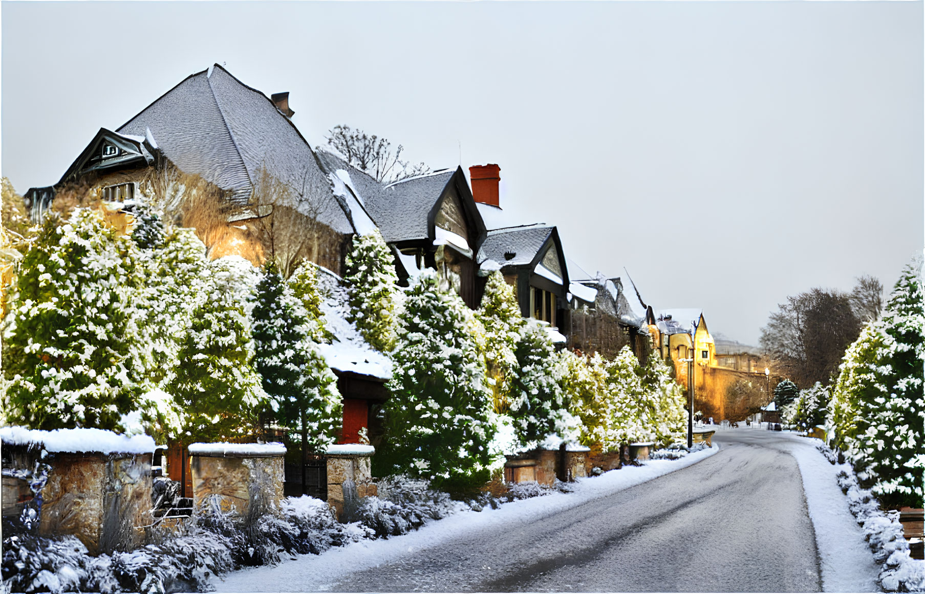 Snow-covered street with traditional stone houses and warm lights at dusk