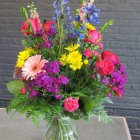 Colorful floral arrangement in clear vase on blue mosaic background