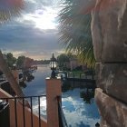 Tranquil riverside watercolor with greenery, fence, jetty, and sculpture