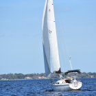 White Sailboat Sailing on Blue Water with Hazy Shoreline Background