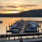 Tranquil lakeside town at sunset with mountains, boats, and cozy house