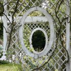 Intricate ironwork garden gate among lush pink and yellow flowers