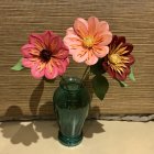 Vibrant paper vase with oversized flowers on beige background with leaf patterns