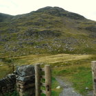 Scenic stone pathway through grassy hills to lake and mountains